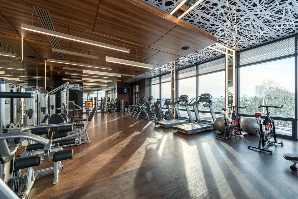 Spacious gym with a wooden ceiling, treadmills and bikes by large windows