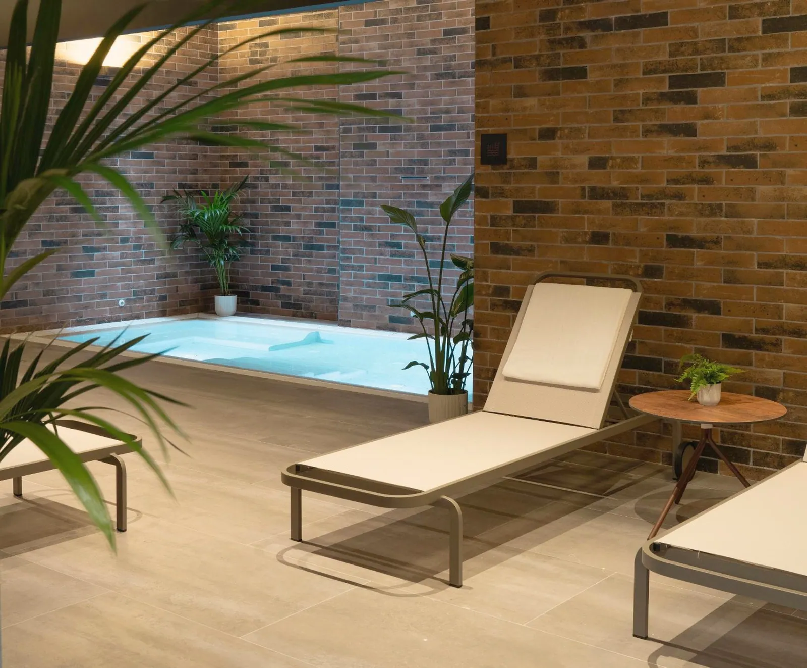 Jacuzzi interior con tumbonas y paredes de ladrillo