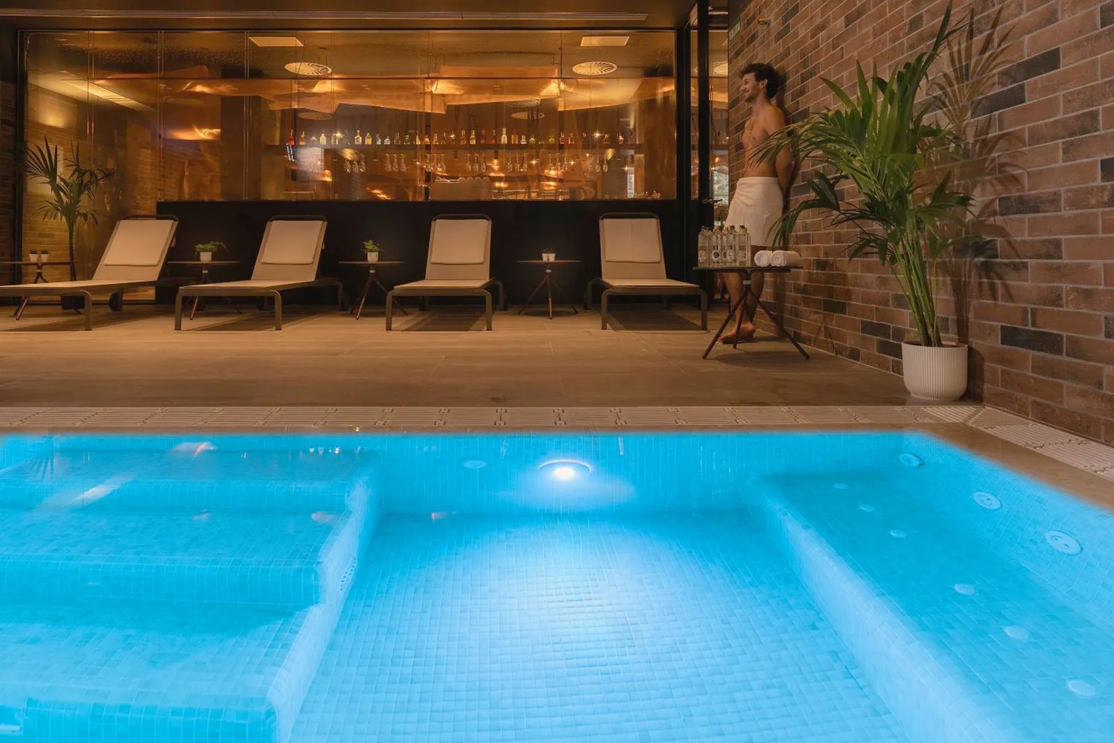 Piscina interior iluminada con tumbonas